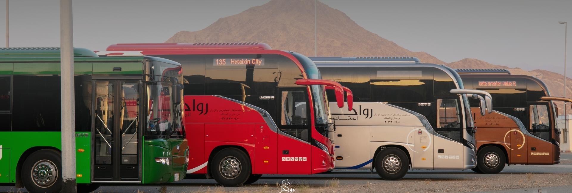 Rawahel buses lined up below the mountains of Makkah